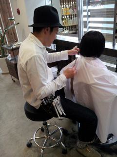 A member of JHDAC gives a haircut for one who wishes and “onewig” is completed.(c) JHDAC